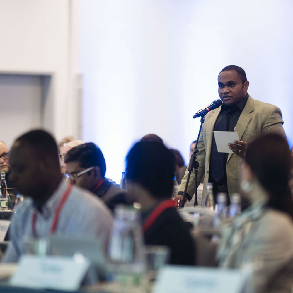 A man stands to speak during the General Meeting