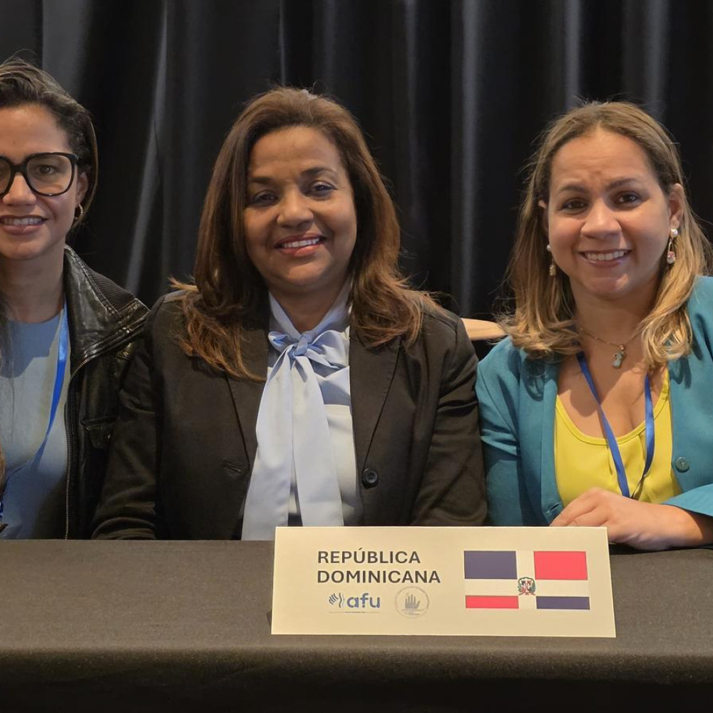 Three professionals sat behind a meeting desk with a card saying Dominican Republic