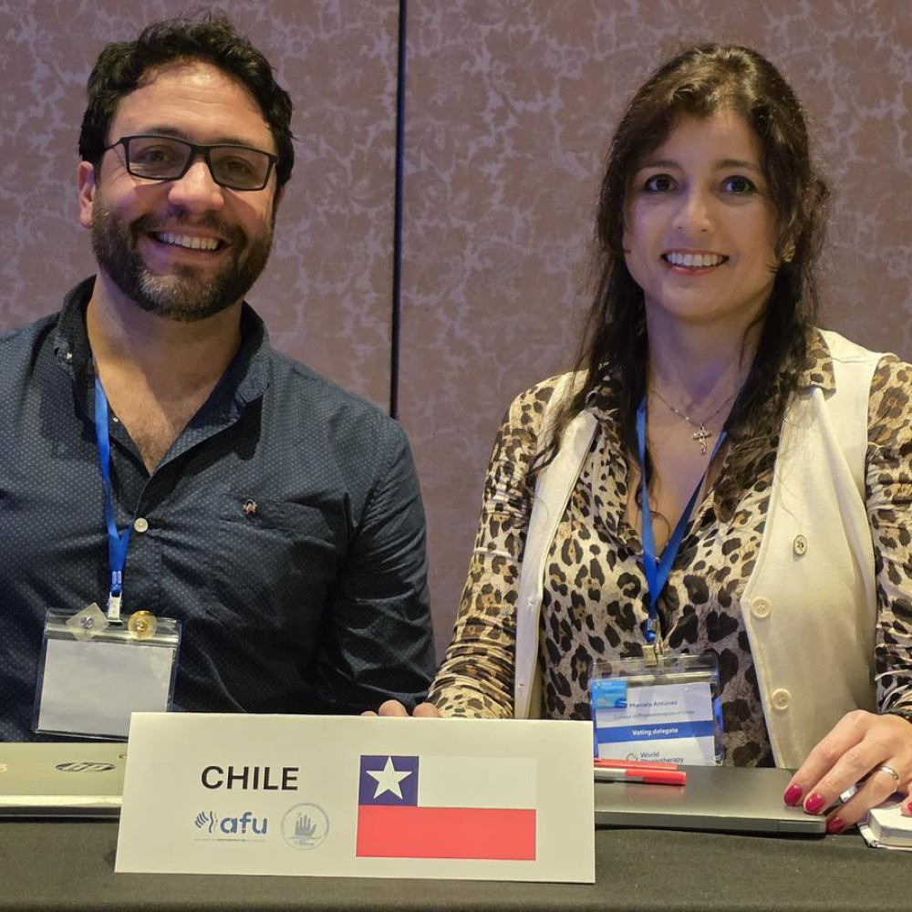Two professionals sat behind a meeting desk with a card saying Chile